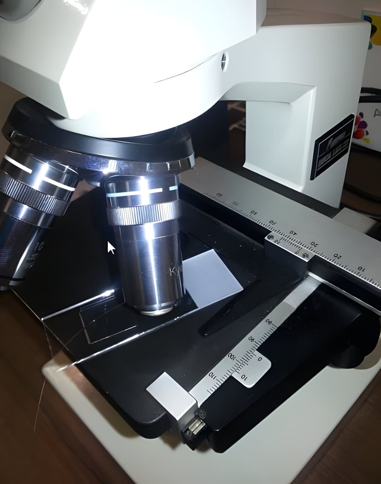 Een microscoop met een preparaatglaasje op de tafel, in het laboratorium van de praktijk.